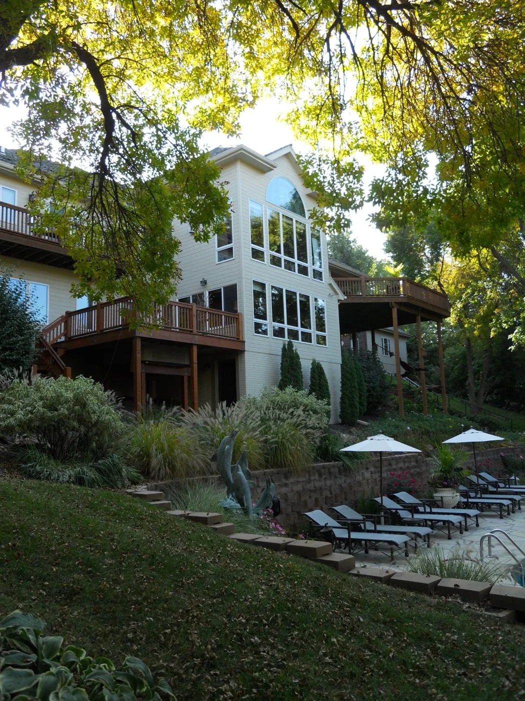 The back of a home with a two-story window wall, stacked decks, and a pool terrace