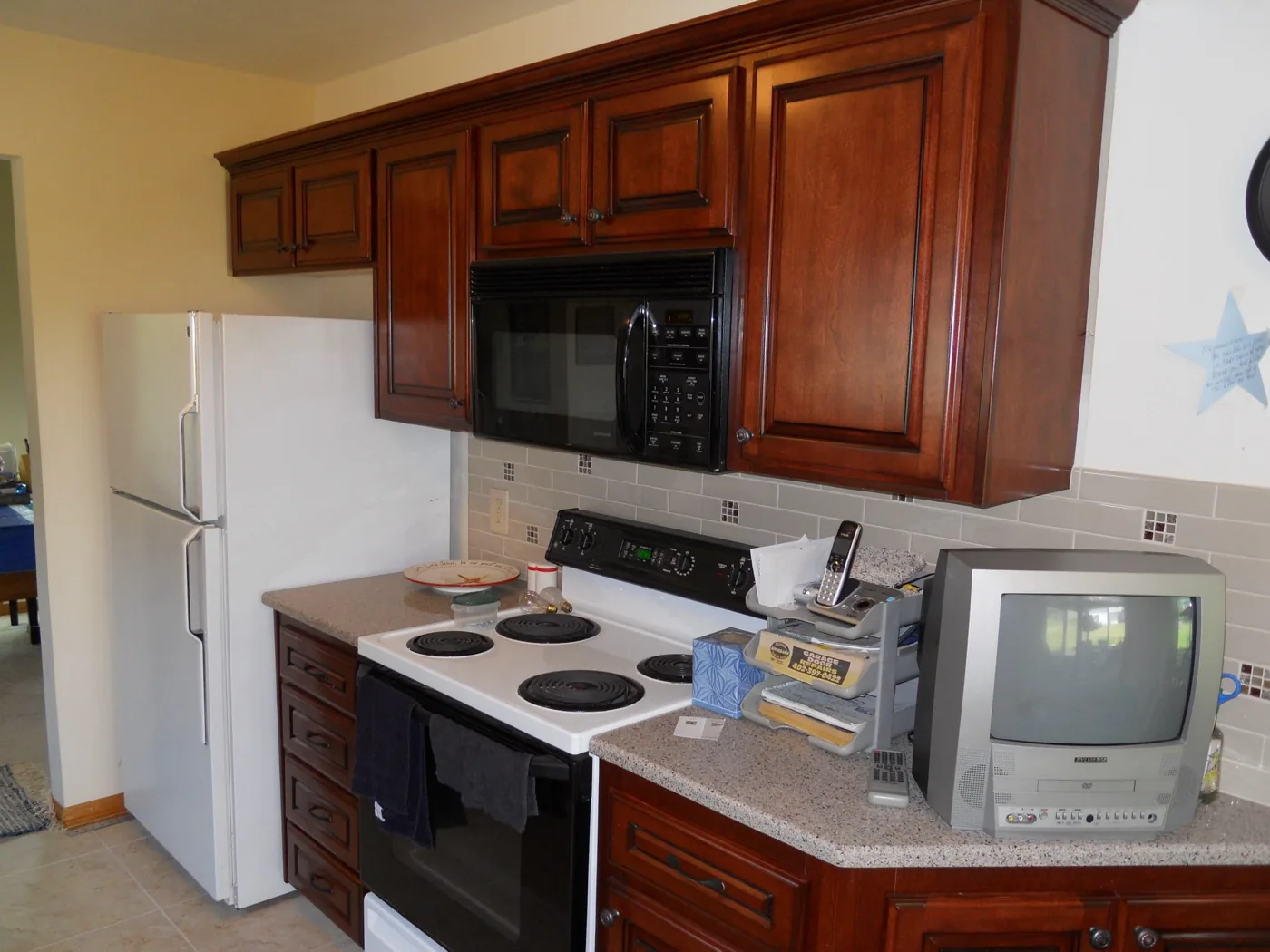 A kitchen with cherry raised-panel cabinets and a tile backsplash