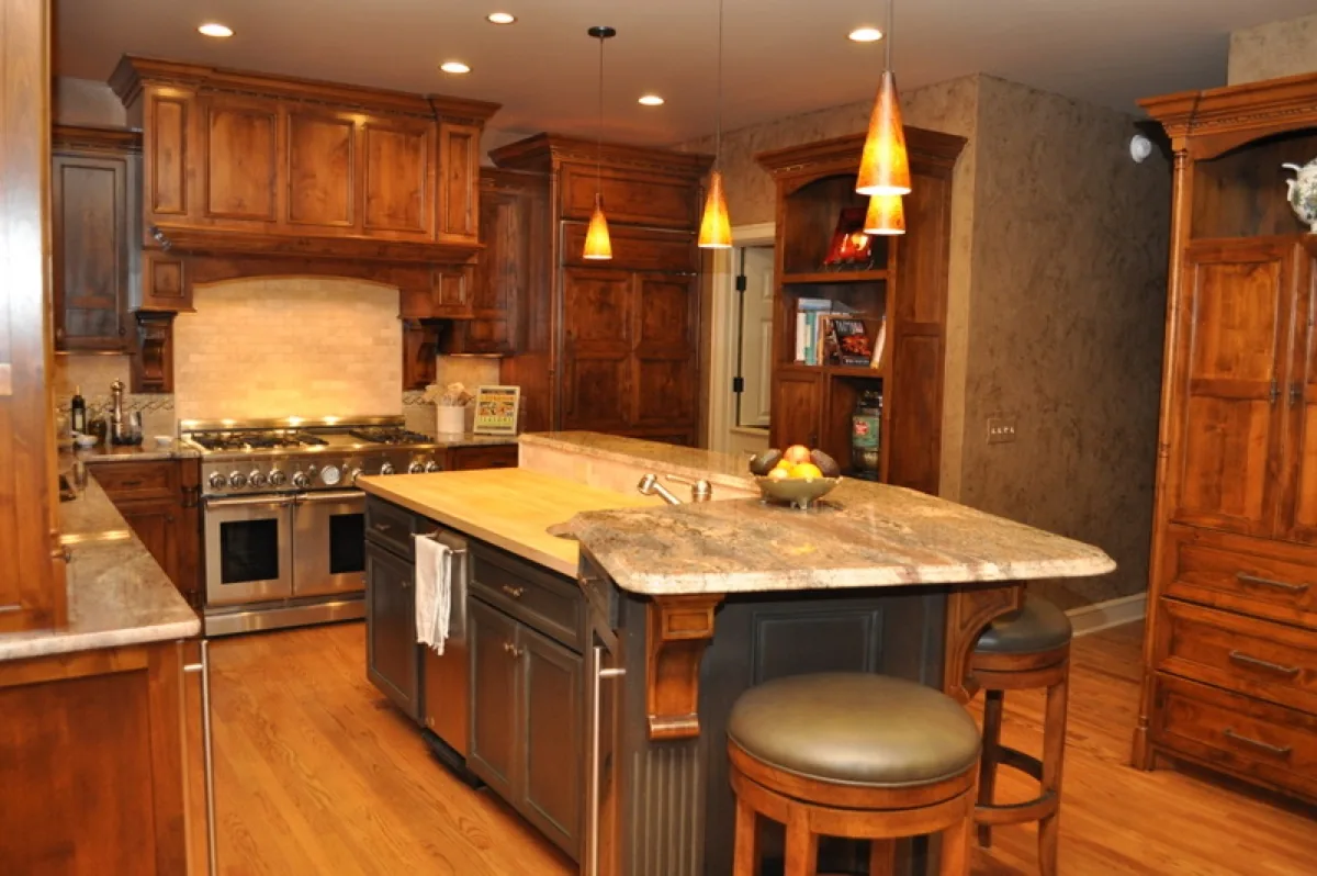 A cherry kitchen with a custom island, a professional range, and pendant lights over the counter